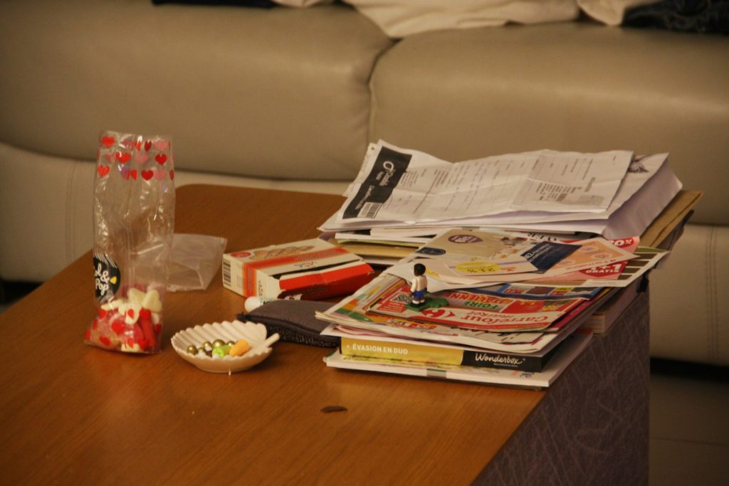 a wooden table topped with magazines and a vase
